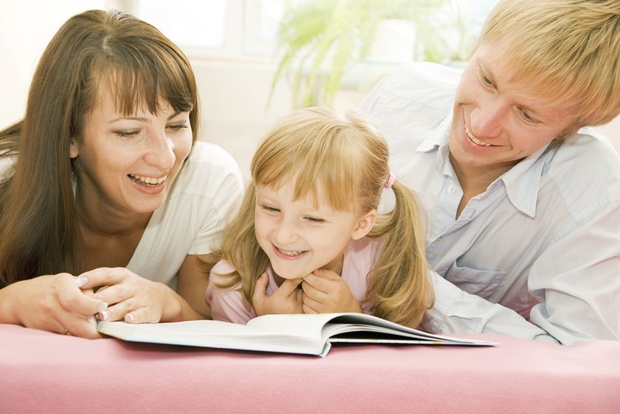 Portrait of happy family reading the book together at home