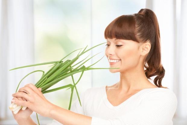 bright picture of beautiful housewife with spring onions in kitchen