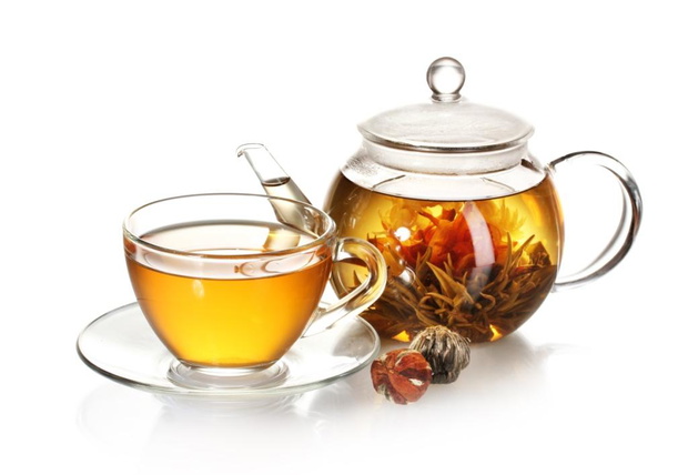 exotic green tea with flowers in glass teapot and cup isolated on white