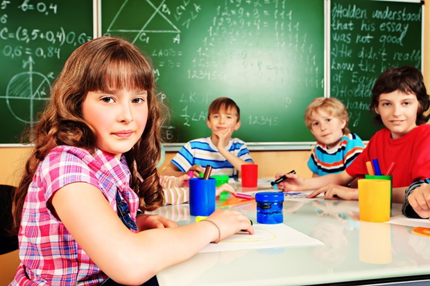 Group of school children studying in classroom.