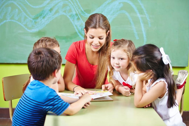 Erzieherin und Kinder lesen Buch in Kita