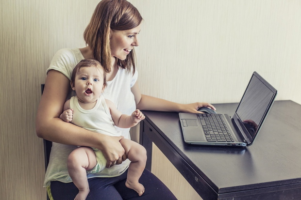 The mother of the woman with the child on hands at work behind the laptop