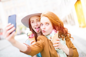 Kobiety jedzące lody w wafelku robiące sobie selfie