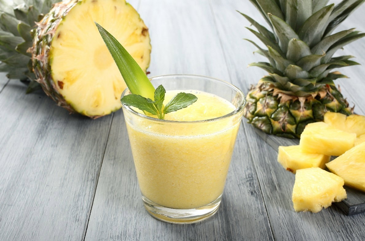 Ananas na stole, obok szklanka z sokiem z ananasa