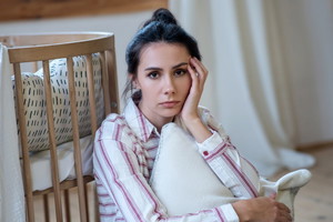 Zmęczona kobieta przy łóżku