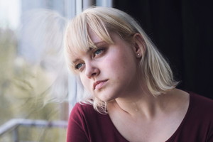 Smutna blondynka w oknie