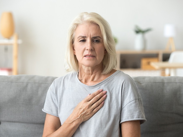Upset stressed mature older woman feeling heartache touching che