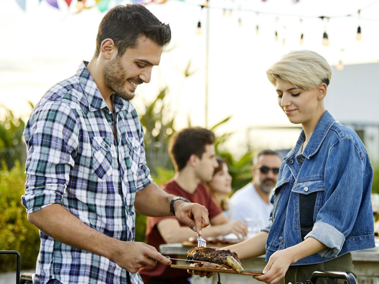 Man serving meat prepared on grill during Asado