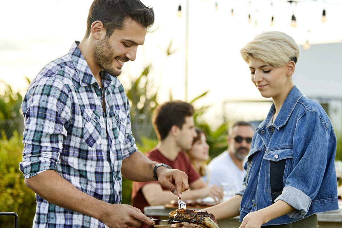Man serving meat prepared on grill during Asado
