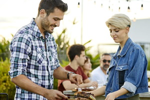 Man serving meat prepared on grill during Asado