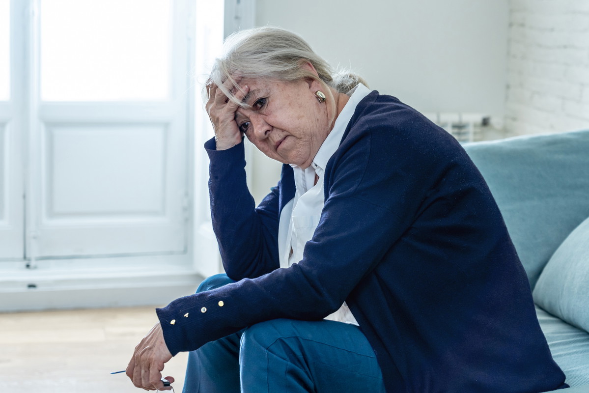 Lonely depressed senior old widow woman crying on couch in isolation at home, feeling sad and worried missing husband and family in COVID-19 Outbreak, lockdown, social distancing and Mental health.