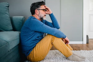 Depressed man sitting alone on the floor