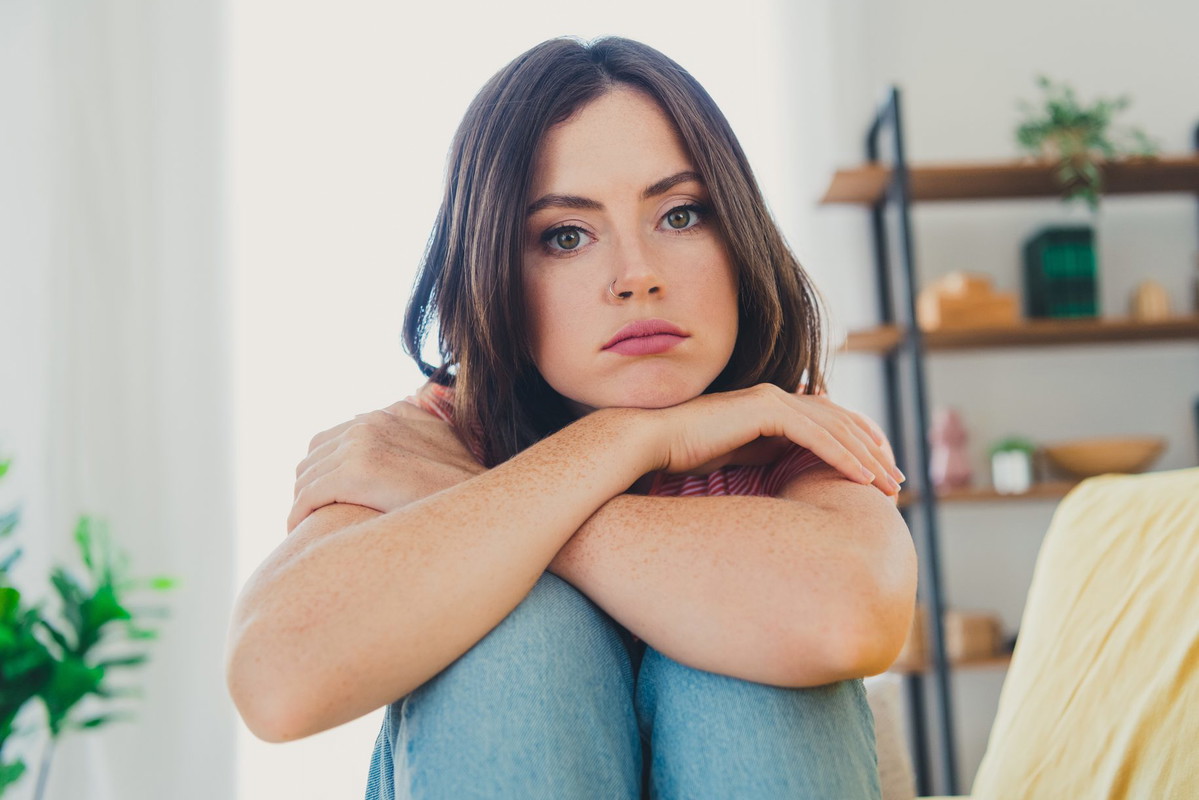 Young woman with stylish bob hair relaxing indoors in a cozy apartment living room, feeling calm and comfortable