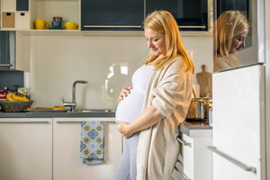 Pregnant Woman with Hands on her Belly Standing in Kitchen