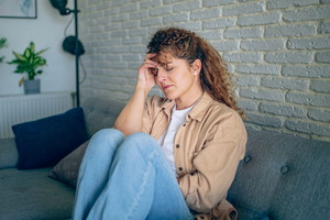 Young woman having a headache on a sofa at home