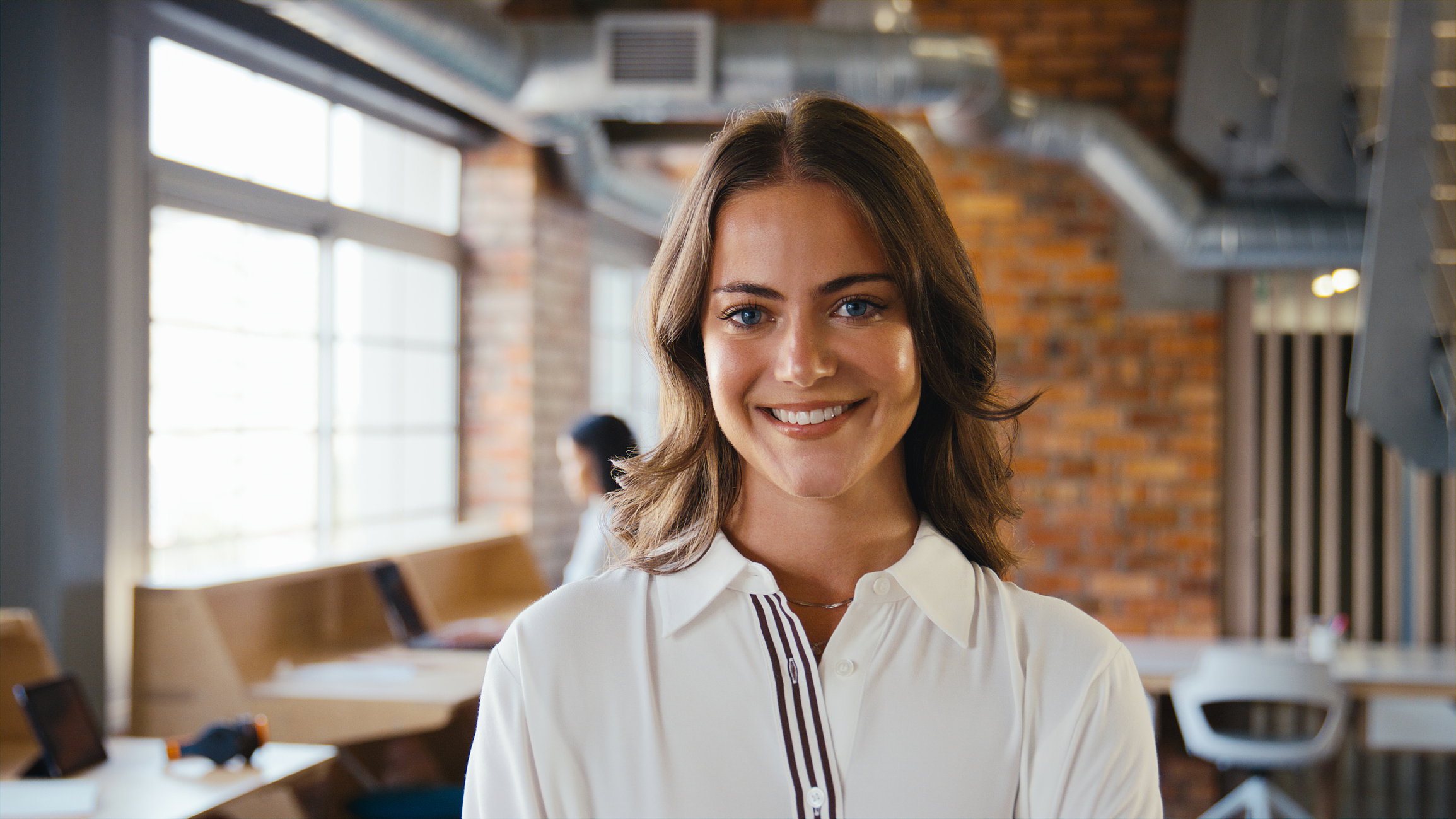 Portrait Of Smiling Young Businesswoman Working In Modern Open Plan Office