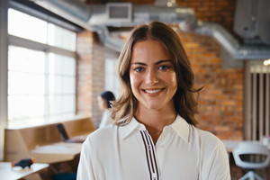 Portrait Of Smiling Young Businesswoman Working In Modern Open Plan Office