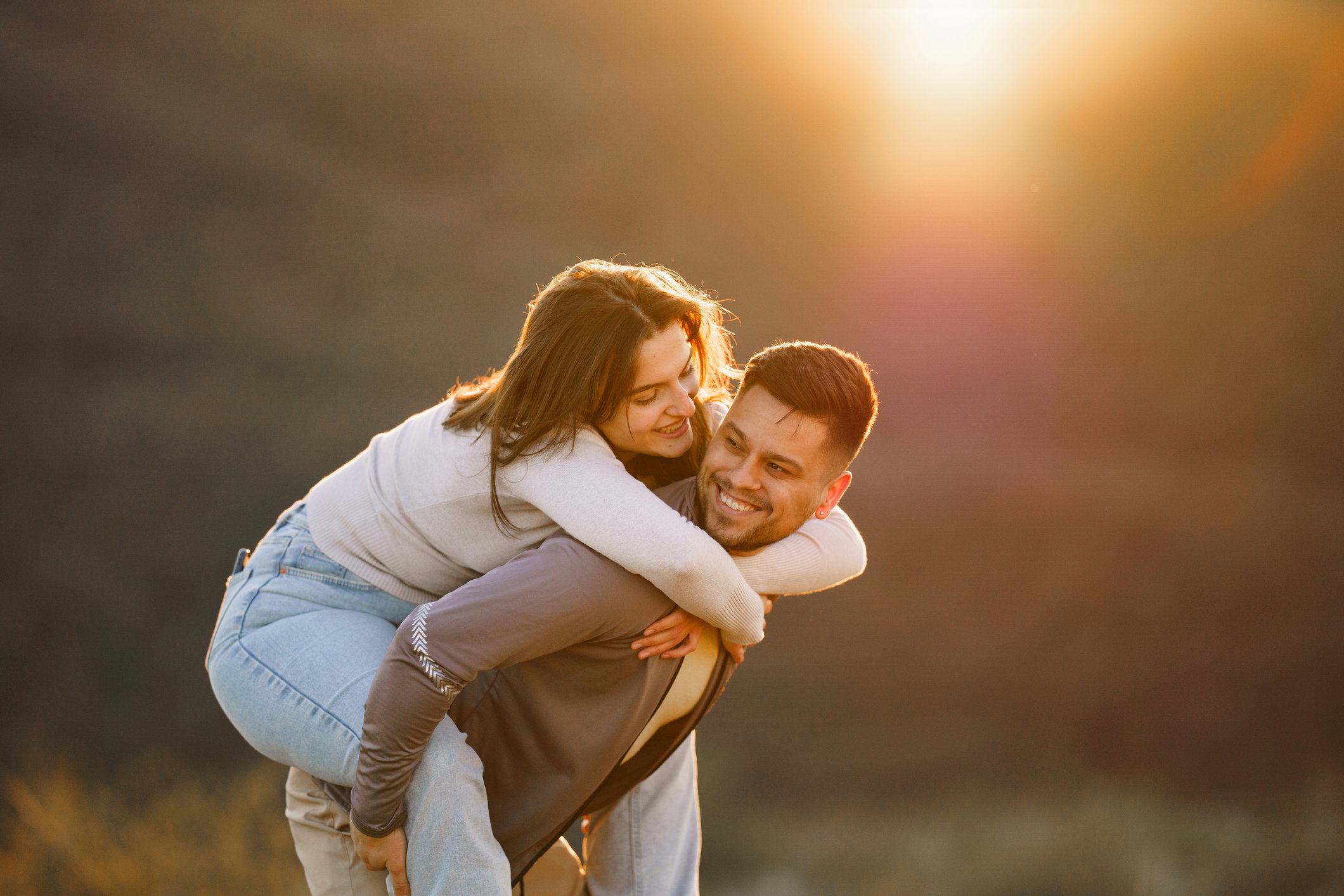 Happy couple piggy back in the nature