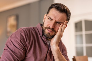A portrait of a man with a worried expression, conveying a sense of concern or uncertainty. Emotions of stress, anxiety, or deep thought, mental health, stress, and human emotions