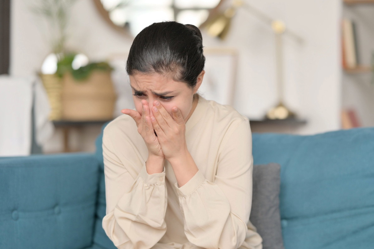 Young Indian Woman Sitting and Crying on Sofa