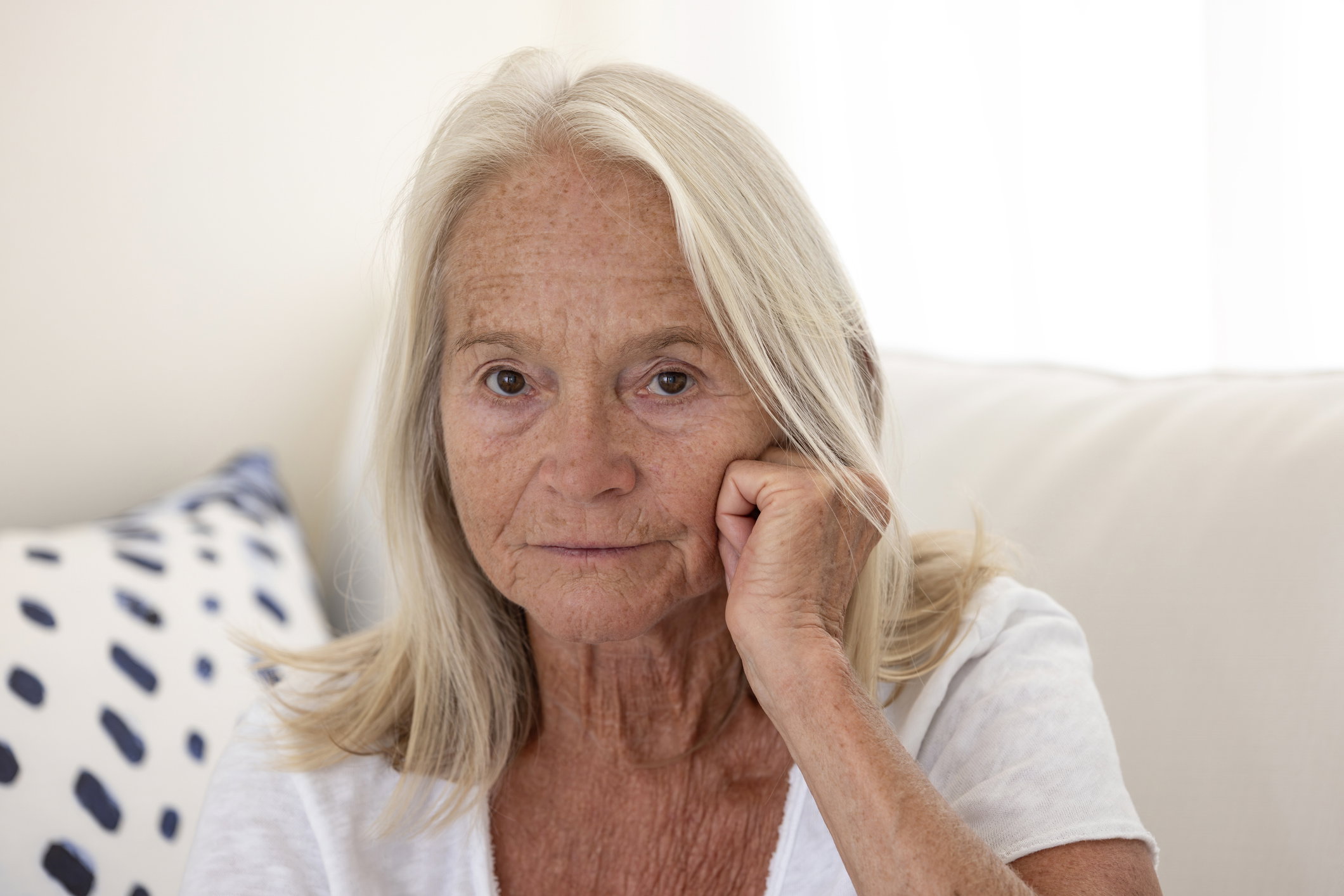 Portrait of beautiful senior woman with hand on chin, looking at camera, background with copy space
