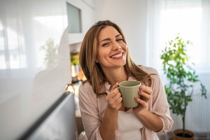 Peaceful quiet morning - A young woman enjoys her morning coffee in her kitchen