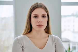 Headshot portrait of young serious woman posing in home