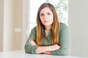 Beautiful young woman at home skeptic and nervous, disapproving expression on face with crossed arms. Negative person.