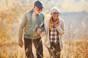 Happy mature couple walking through tall grass in autumn day.