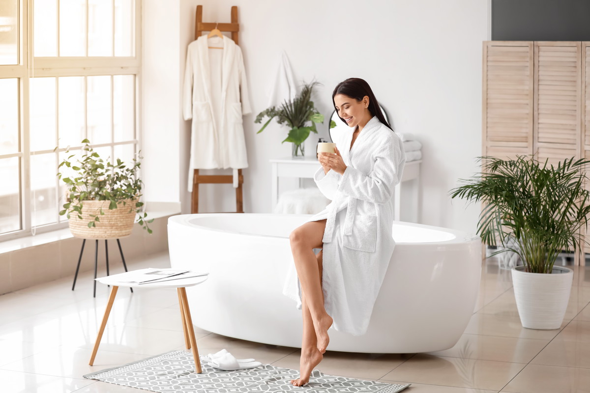 Beautiful young woman drinking coffee in bathroom