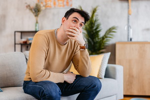 Sad Young Man Sitting On The Sofa At Home