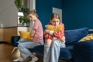 Upset frustrated mother and teenage daughter ignoring each other after quarrel at home, not talking