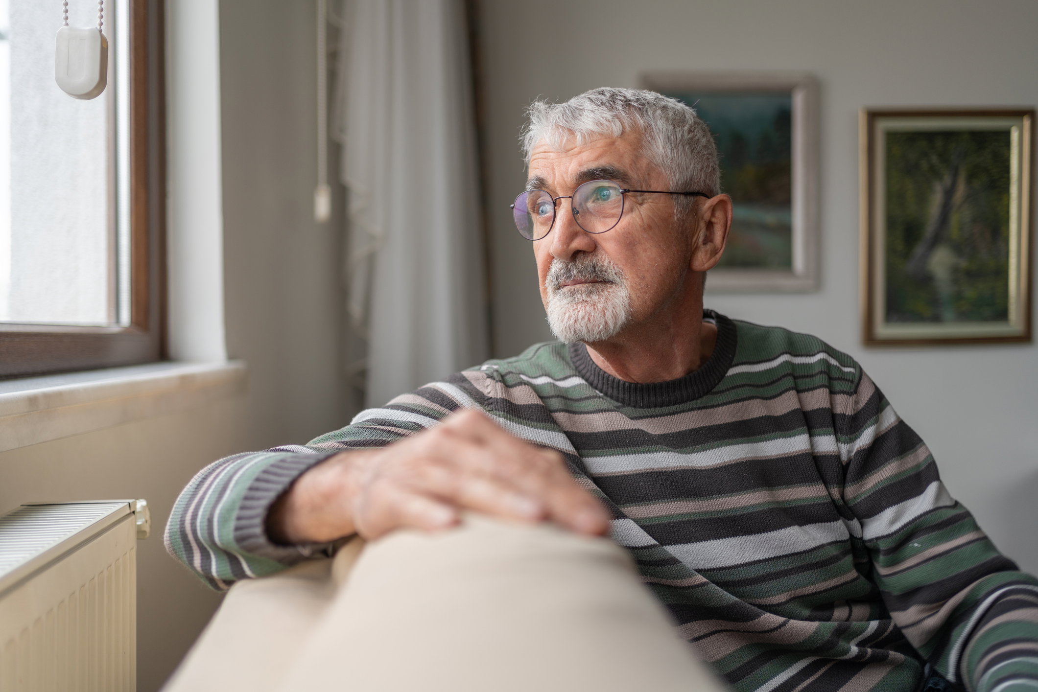 Senior Man Looking Out The Window At Home
