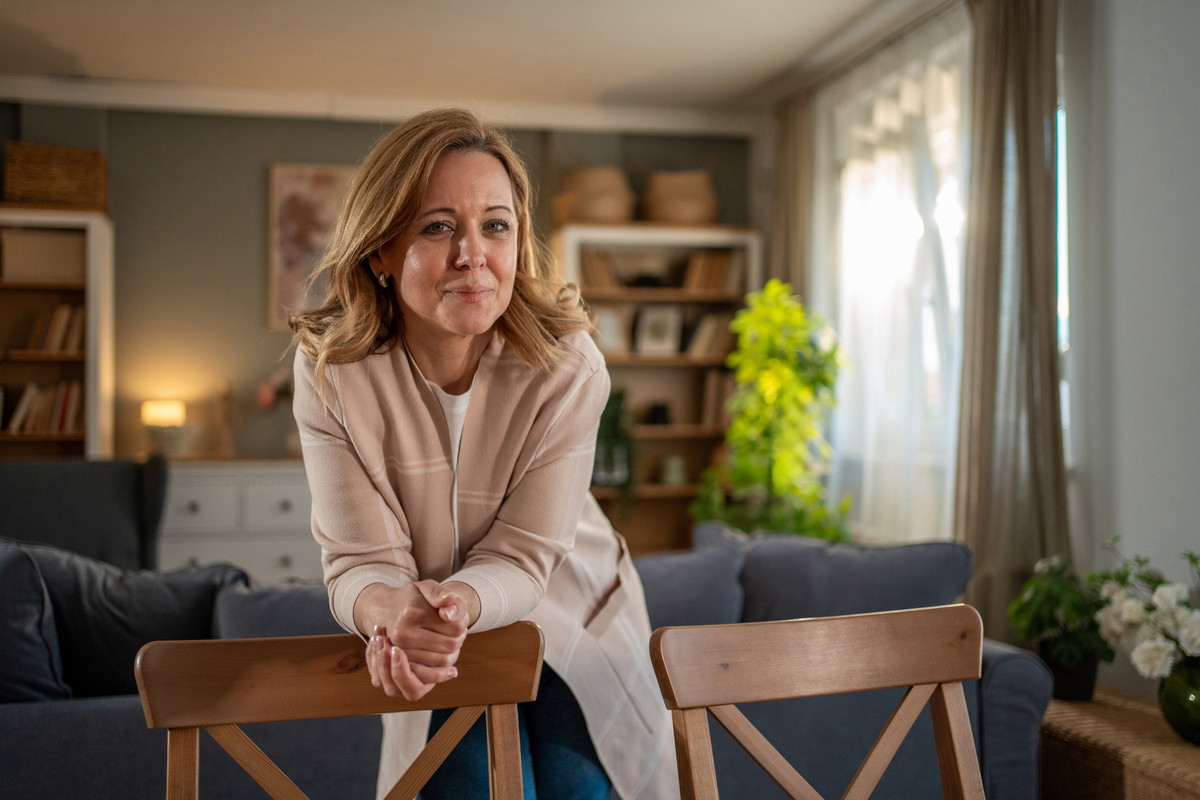 Confident mid adult woman leaning on chairs in living room