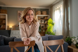 Confident mid adult woman leaning on chairs in living room