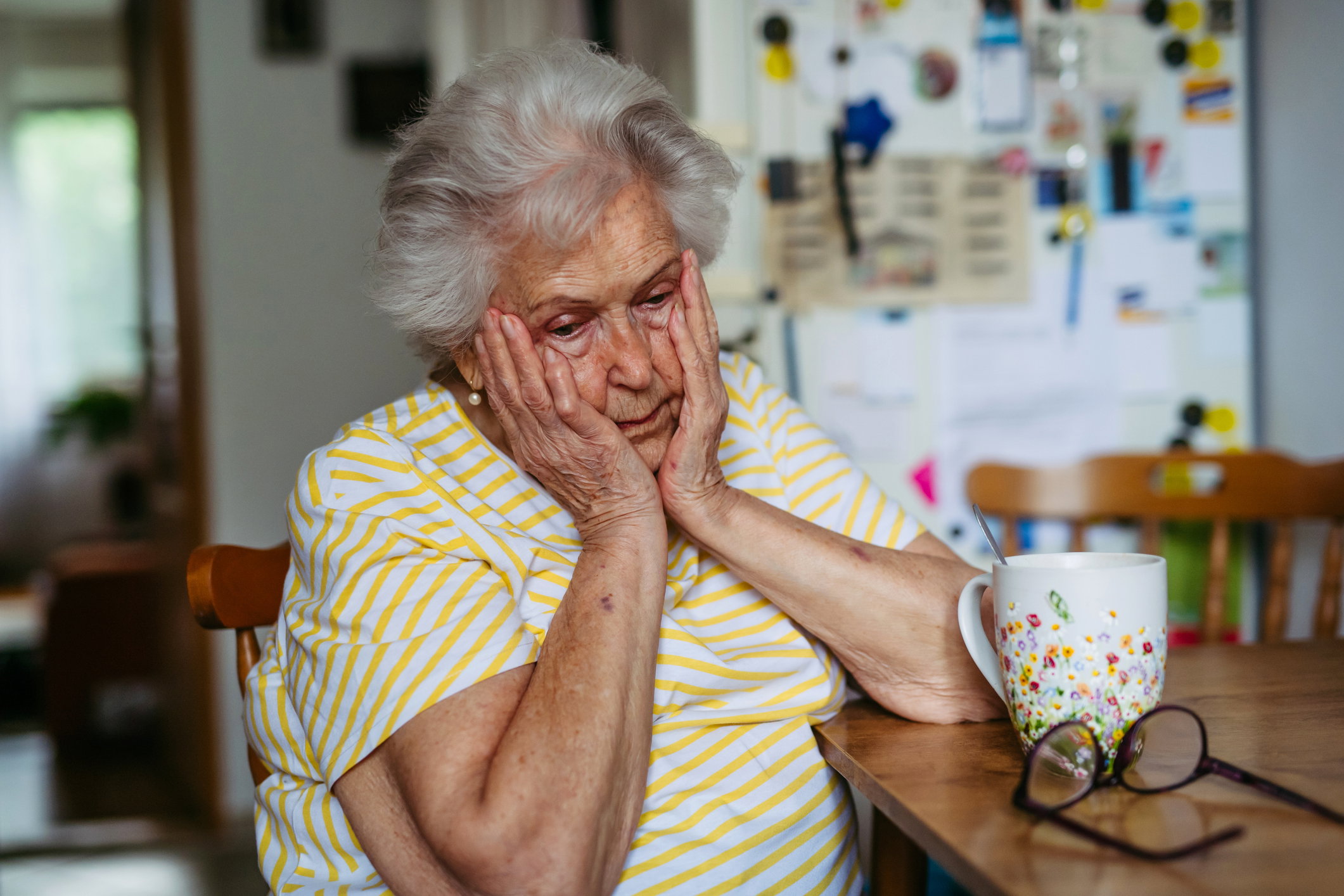 Portrait of worried senior woman crying in kitchen.