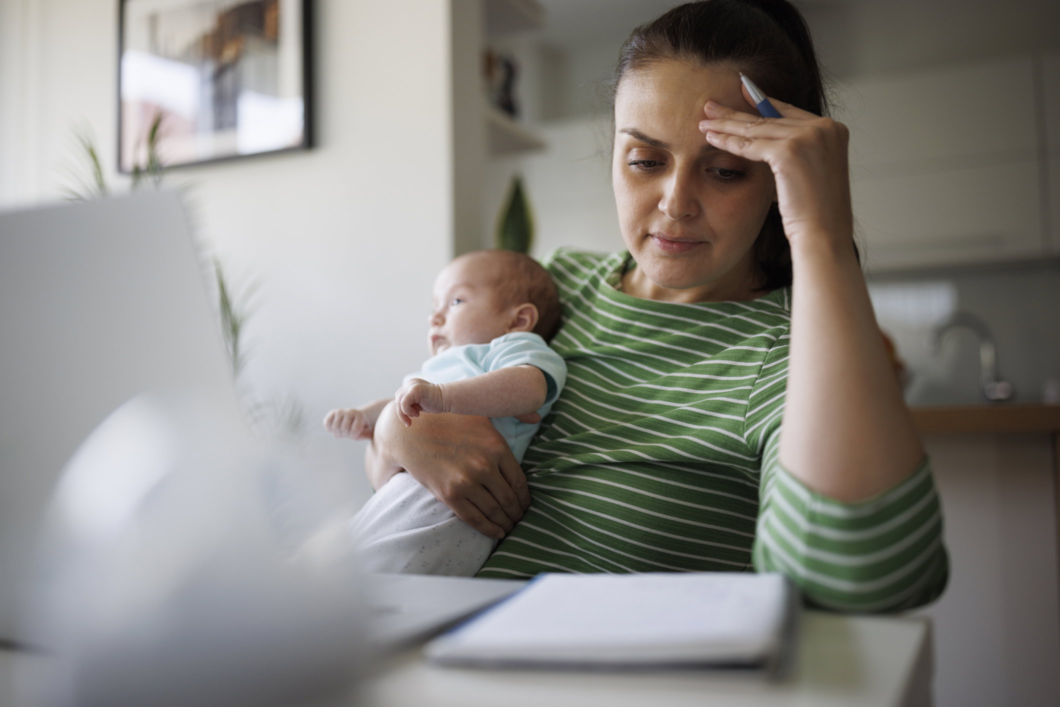 Tired and worried mother working at home