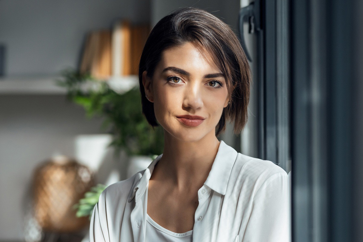 Beautiful woman posing while standing next to the window at home