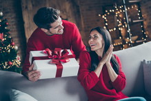 Portrait of his he her she nice attractive lovely sweet charming cheerful cheery glad married spouses guy giving latin hispanic girl eve noel gift in decorated loft industrial style interior