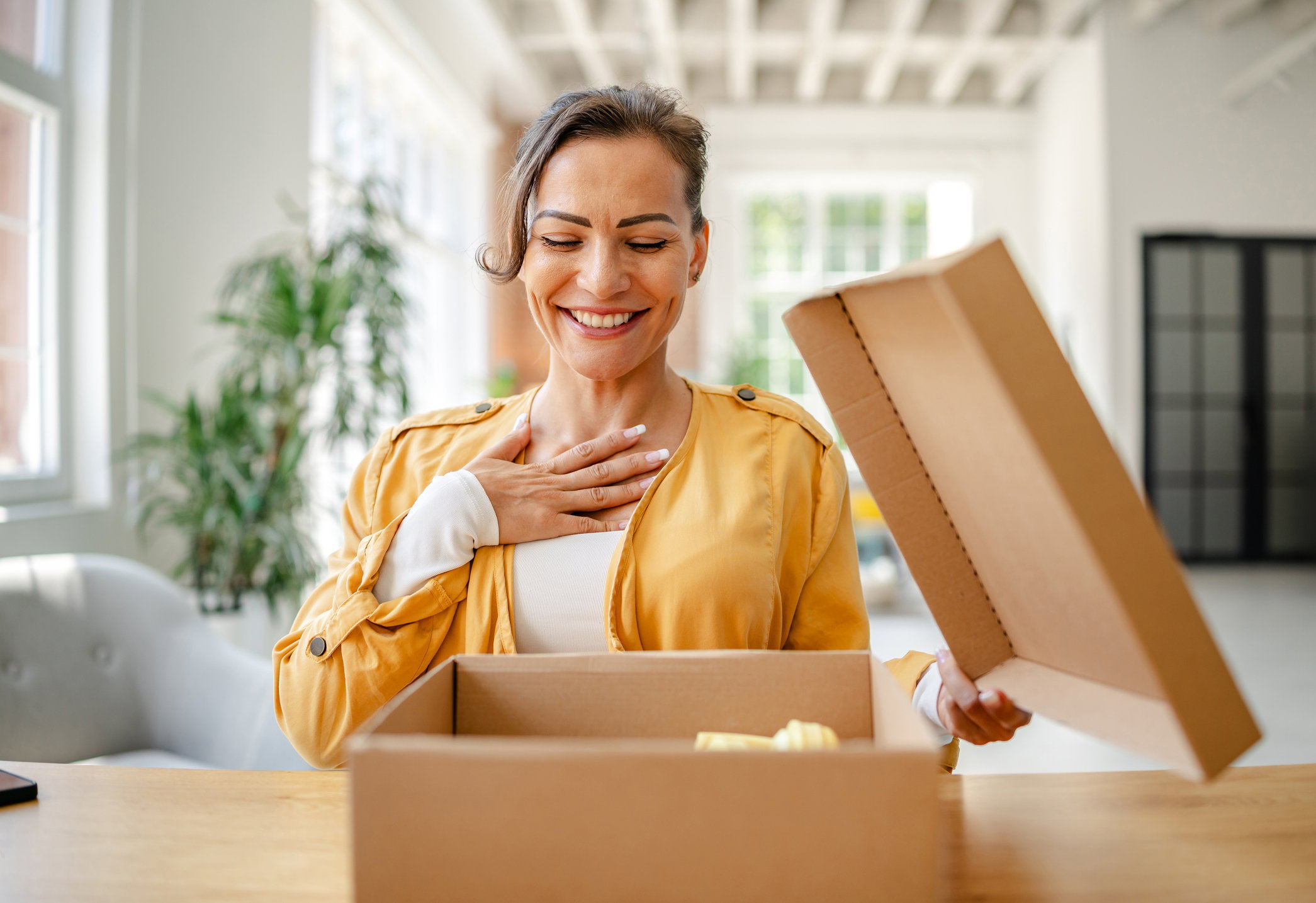 Woman unboxing a surprise gift in a bright modern living room during daytime