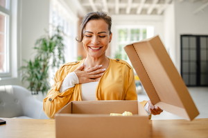 Woman unboxing a surprise gift in a bright modern living room during daytime