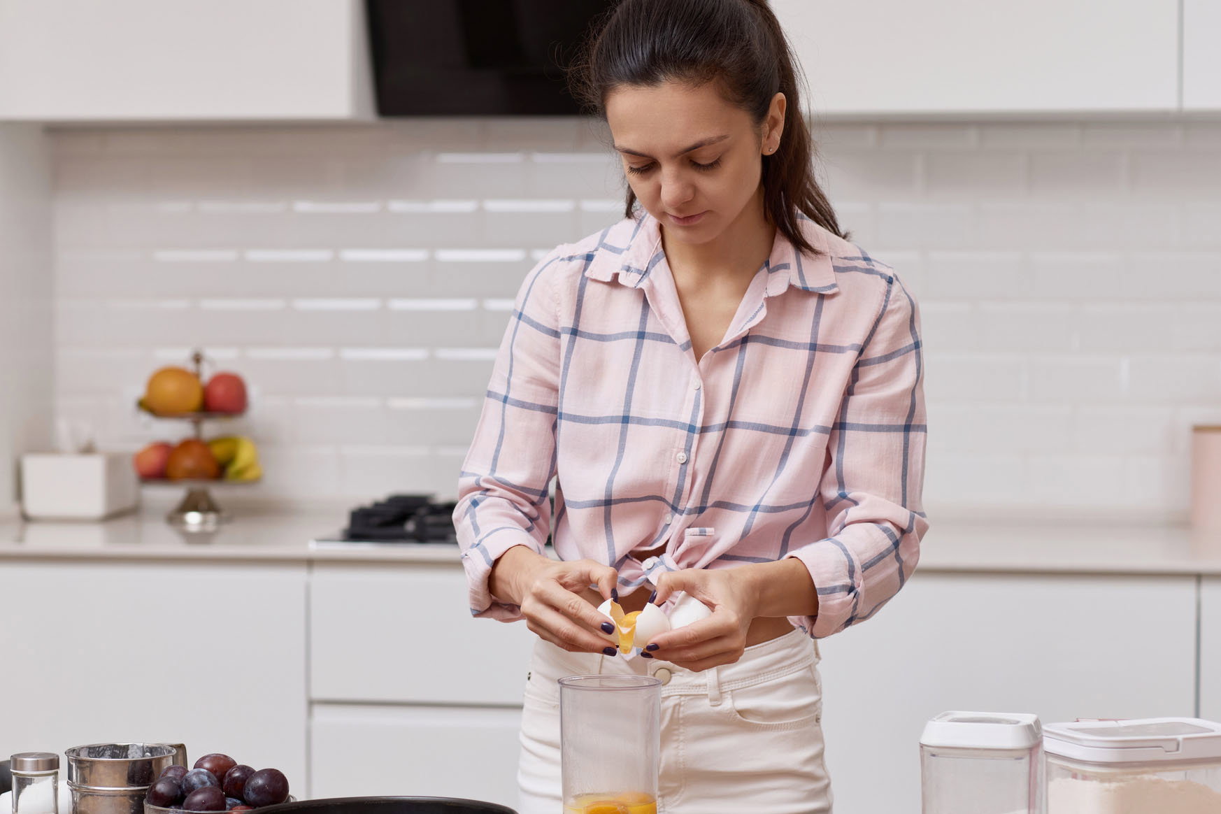 young woman preparing dough and cracking eggs