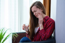 Young woman suffering and experiencing strong aching toothache. Tooth decay and sensitivity. Diseases gums