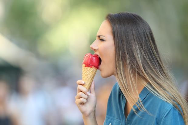 Woman with hypersensitivity biting an ice cream