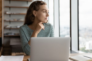 Zamyślona kobieta przy laptopie
