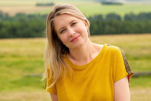 kobieta w wieku 40 plus blondynka w żółtej bluzce stoi na dworze i uśmiecha się rozmarzona