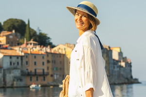 kobieta w wieku 45 plus w kapelusz w mieście Rovinj w Chorwacji Istria stoi uśmiechnięta na tle starego miasta