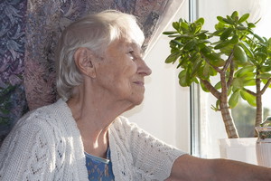 smutna seniorka w oknie