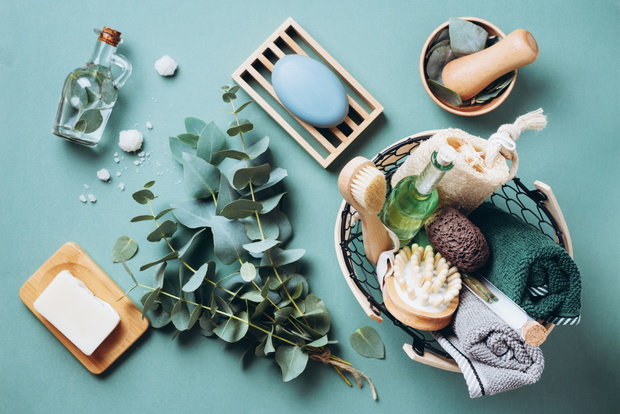 Wooden soap dish, soap, eucalyptus over green background. Zero waste, natural organic bathroom tools. Plastic free life. Ecological skin care, body treatment concept