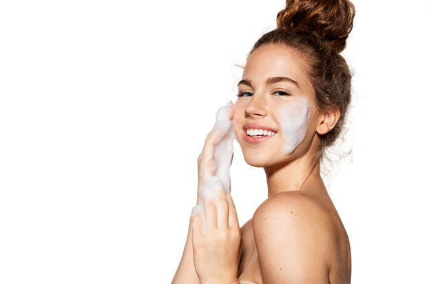 Happy woman smiling and applying cosmetic foam on face